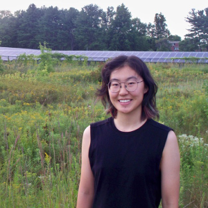 Picture of Eris Gao standing in a field with solar panels behind them