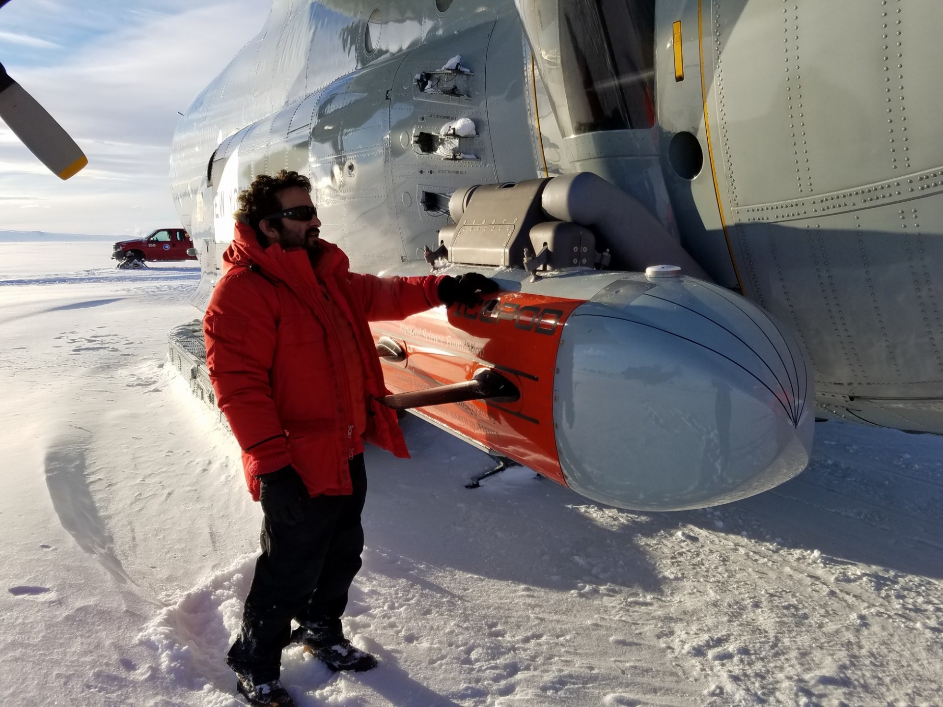 IcePod Engineer with Pod in Antarctica. Photo: Beth Burton IcePod Engineer with the IcePod attached to aircraft in William's Field, Antarctica. Photo: Beth Burton (USGS)